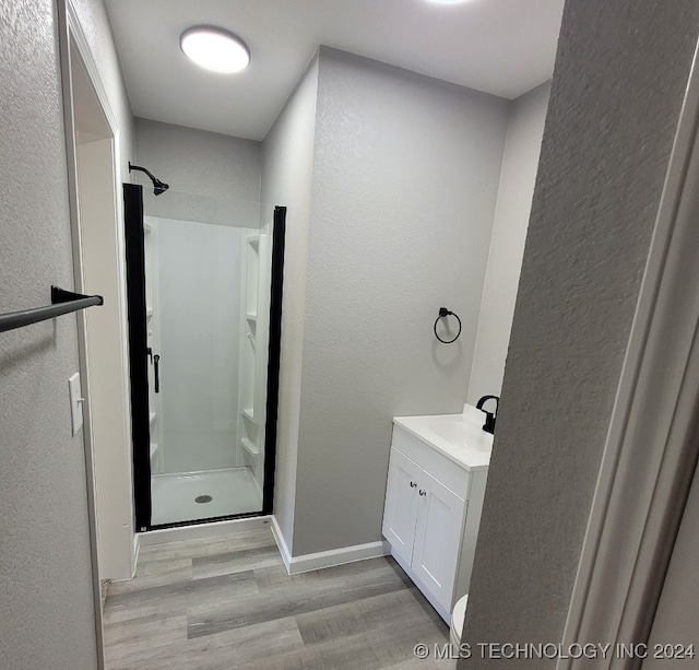 bathroom featuring walk in shower, hardwood / wood-style flooring, and vanity