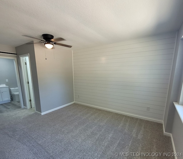 carpeted spare room featuring ceiling fan and a textured ceiling