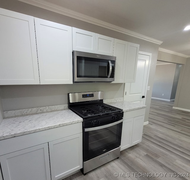 kitchen featuring light hardwood / wood-style flooring, light stone counters, stainless steel appliances, ornamental molding, and white cabinets