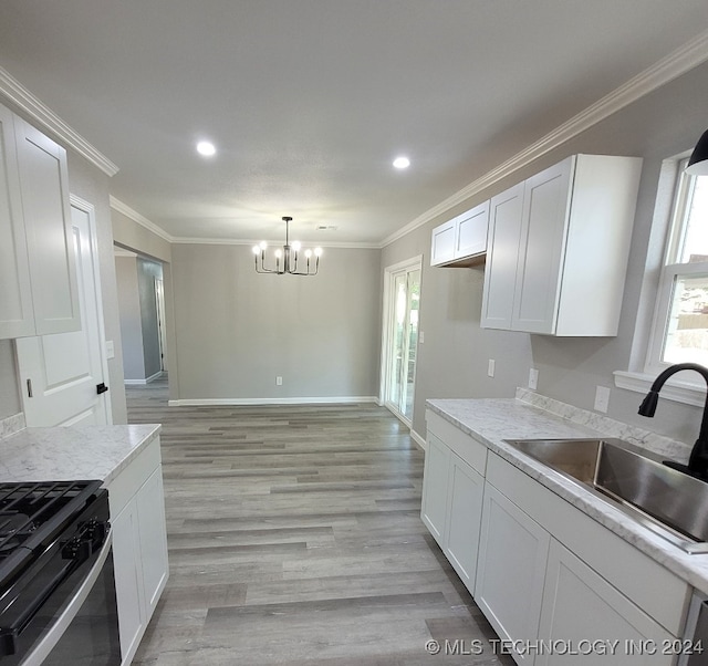 kitchen featuring light stone counters, white cabinets, pendant lighting, sink, and light hardwood / wood-style flooring