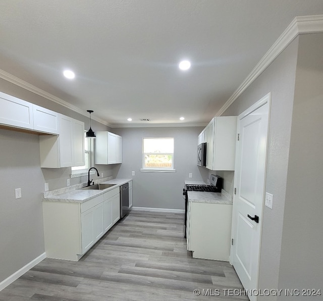 kitchen featuring light wood-type flooring, sink, hanging light fixtures, appliances with stainless steel finishes, and white cabinetry