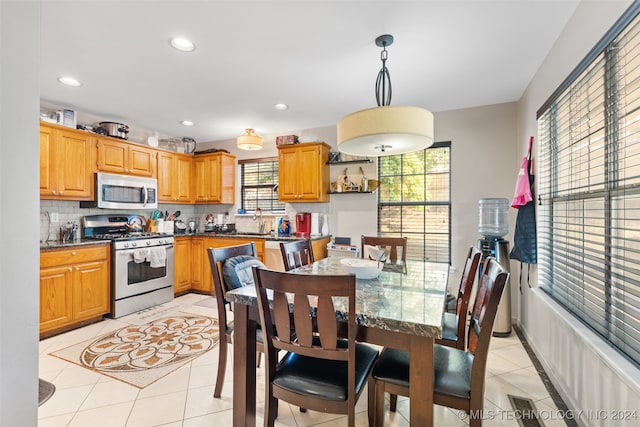 kitchen featuring appliances with stainless steel finishes, tasteful backsplash, hanging light fixtures, and light tile patterned floors