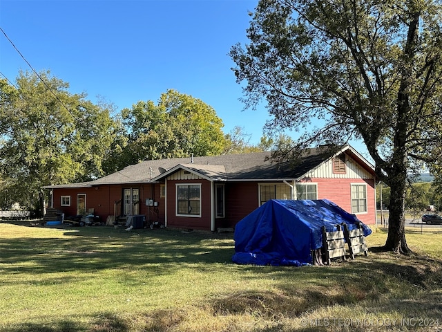 back of house featuring central air condition unit and a yard