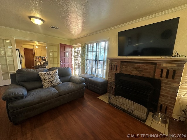 living room with crown molding, hardwood / wood-style flooring, ceiling fan, a fireplace, and a textured ceiling