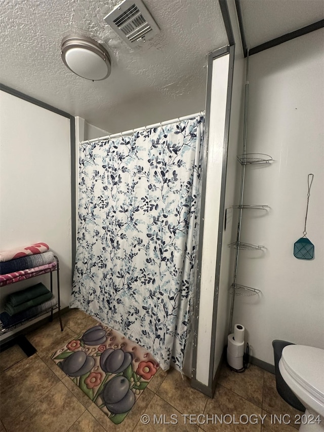 bathroom with tile patterned floors, a textured ceiling, toilet, and walk in shower