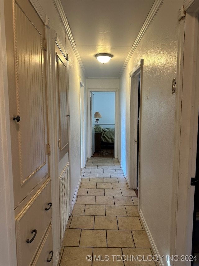 hallway with ornamental molding and light tile patterned floors