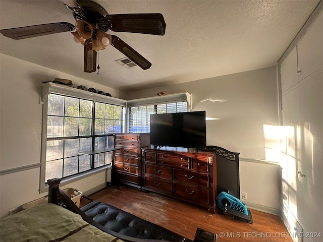 bedroom with hardwood / wood-style floors, a textured ceiling, and ceiling fan