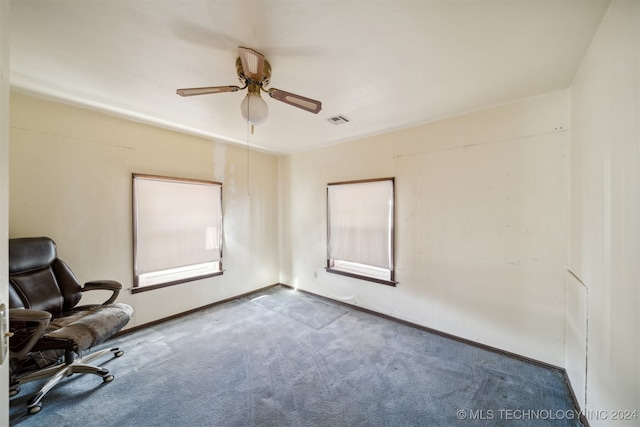 unfurnished office featuring carpet flooring, baseboards, visible vents, and a ceiling fan