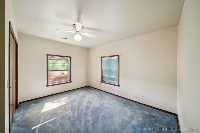 carpeted empty room with visible vents, baseboards, and ceiling fan