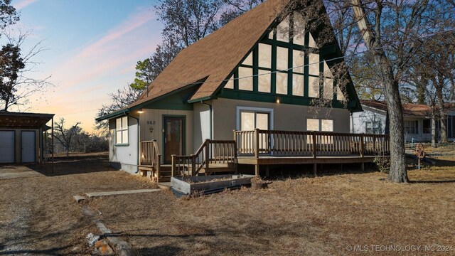 back house at dusk with a deck and an outbuilding