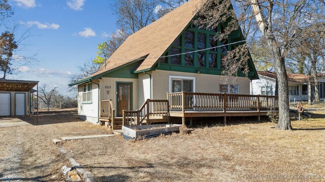 back of house with an outdoor structure, a deck, and a garage