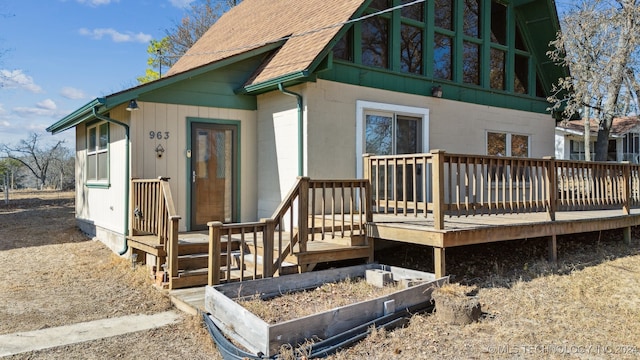 rear view of property featuring roof with shingles and a wooden deck