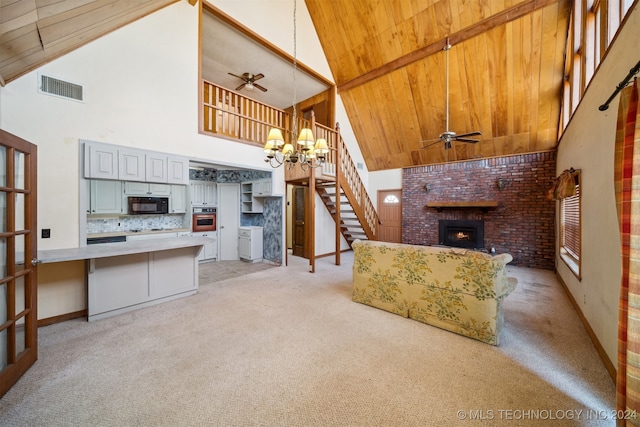 living area with visible vents, light carpet, ceiling fan with notable chandelier, stairway, and a fireplace