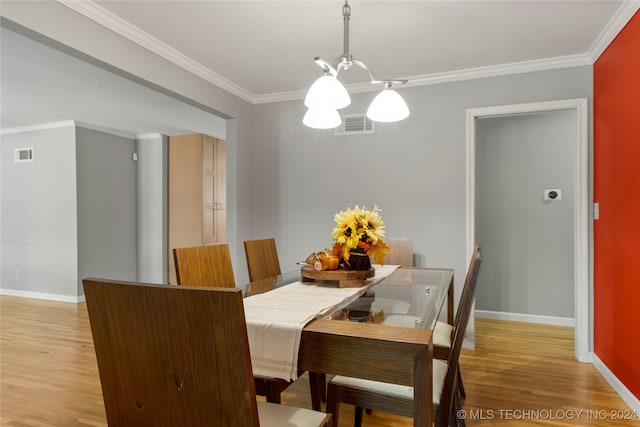 dining area featuring a notable chandelier, ornamental molding, and light wood-type flooring