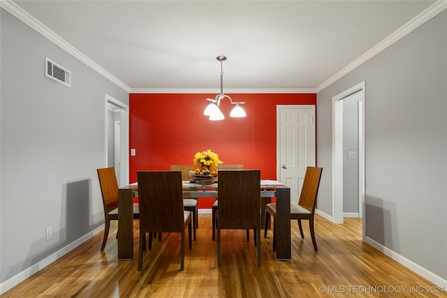 dining room with a notable chandelier, crown molding, and hardwood / wood-style flooring