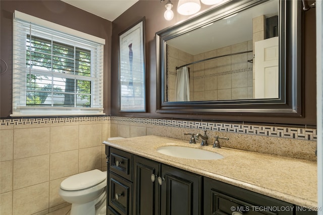 bathroom featuring toilet, vanity, and tile walls