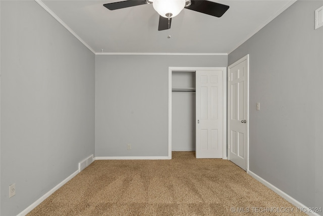 unfurnished bedroom with carpet, crown molding, a closet, and ceiling fan