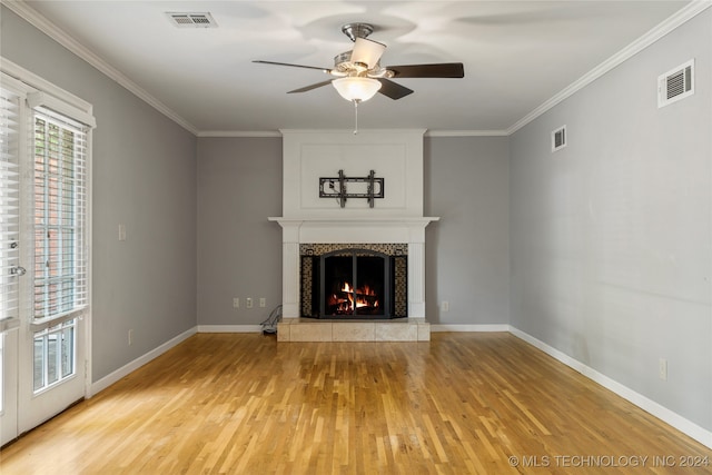 unfurnished living room featuring crown molding, hardwood / wood-style flooring, a tile fireplace, and ceiling fan