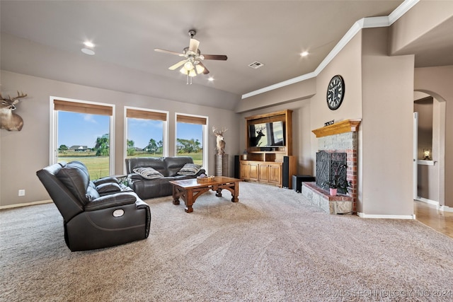 carpeted living room featuring crown molding, ceiling fan, and a fireplace