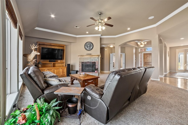 carpeted living room with ornamental molding, a brick fireplace, and ceiling fan