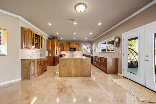 kitchen featuring crown molding, tasteful backsplash, light stone countertops, a kitchen island, and french doors