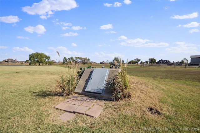 entry to storm shelter with a rural view and a lawn