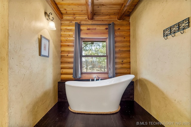 bathroom with beamed ceiling, log walls, a bath, and wooden ceiling