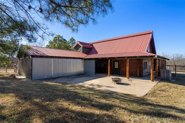 view of front facade featuring a patio area, central AC, a front lawn, and an outdoor fire pit