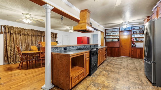 kitchen featuring wood-type flooring, black range with electric cooktop, ornamental molding, decorative columns, and stainless steel refrigerator