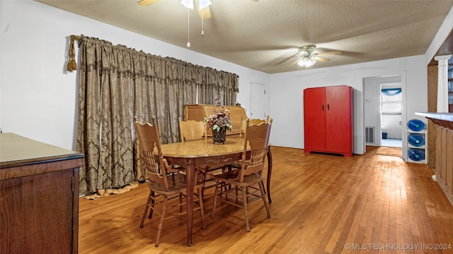 dining space with decorative columns, ceiling fan, hardwood / wood-style flooring, and a textured ceiling