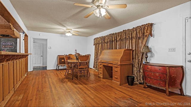 dining area with a textured ceiling, wood-type flooring, and ceiling fan