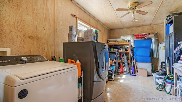 clothes washing area with gas water heater, wooden walls, washing machine and dryer, and ceiling fan