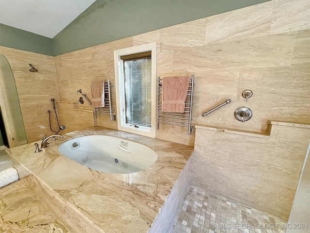 bathroom with tile walls, independent shower and bath, vaulted ceiling, and radiator heating unit