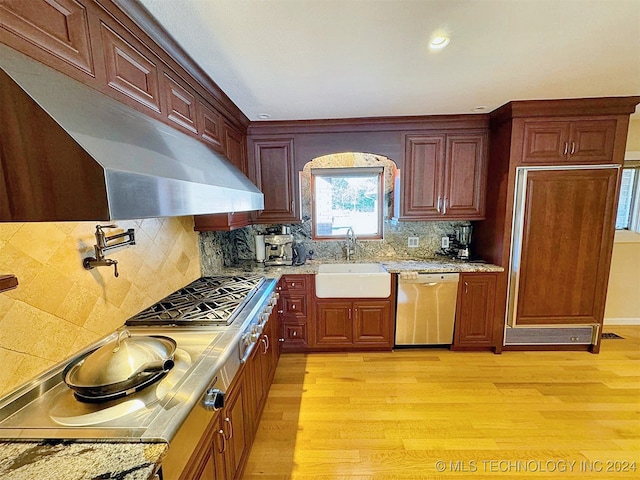 kitchen with light hardwood / wood-style floors, stainless steel dishwasher, sink, and backsplash