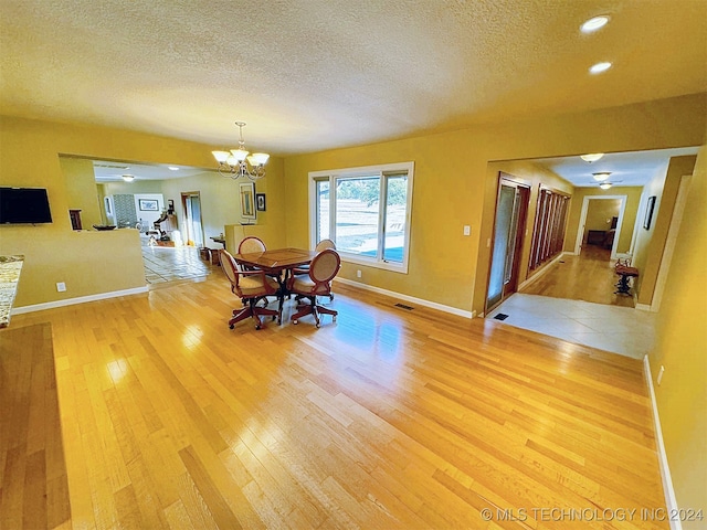 unfurnished dining area featuring a textured ceiling, hardwood / wood-style flooring, and a chandelier