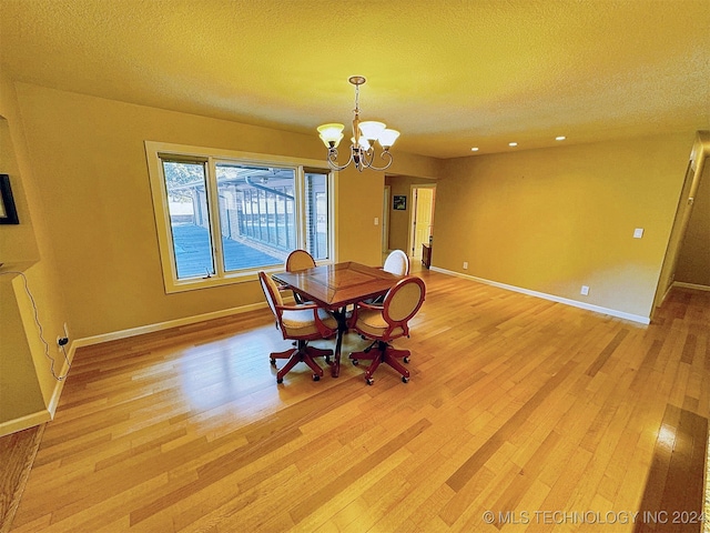 unfurnished dining area with a notable chandelier, a textured ceiling, and light wood-type flooring