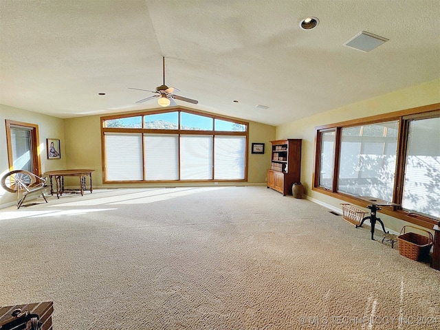 unfurnished living room with vaulted ceiling, a textured ceiling, carpet floors, and ceiling fan