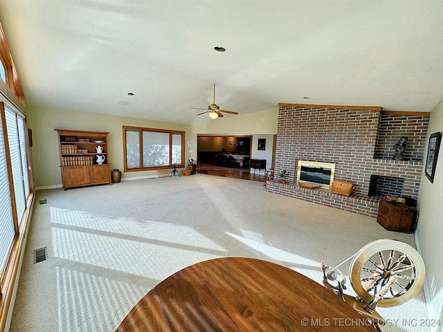 carpeted living room featuring lofted ceiling, a brick fireplace, and ceiling fan