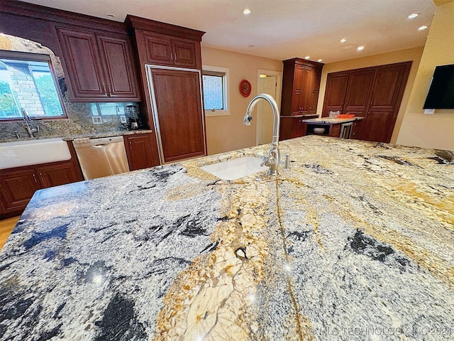 kitchen featuring sink, backsplash, dishwasher, and light stone counters