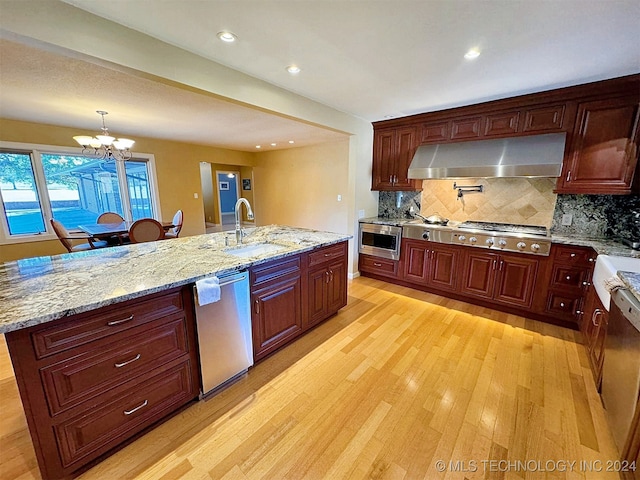 kitchen with an inviting chandelier, a kitchen island with sink, sink, light hardwood / wood-style floors, and stainless steel appliances