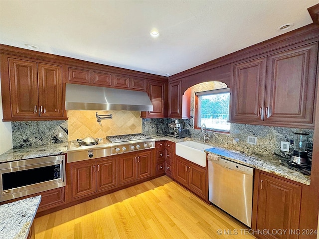 kitchen featuring sink, decorative backsplash, stainless steel appliances, and light wood-type flooring