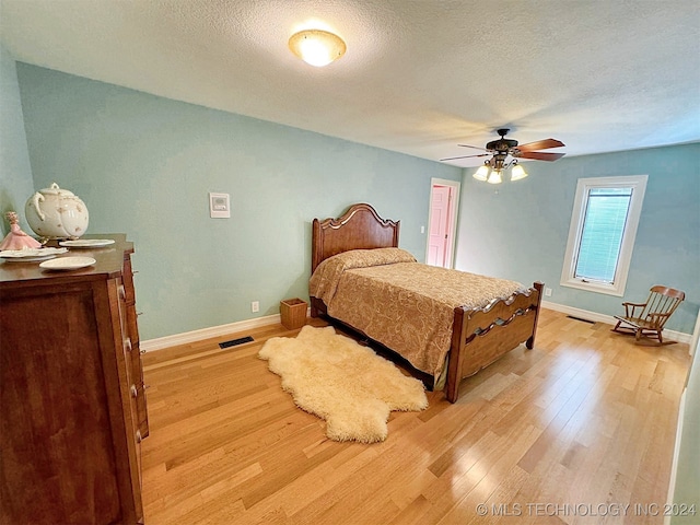 bedroom with a textured ceiling, light hardwood / wood-style floors, and ceiling fan