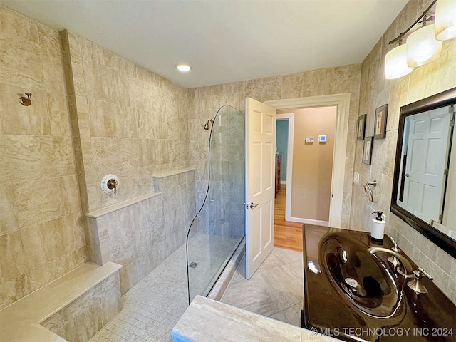 bathroom featuring tile walls, sink, a tile shower, and tile patterned floors