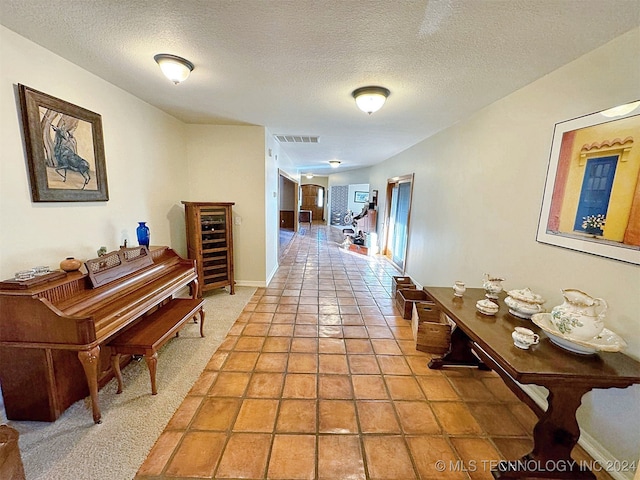 hallway with tile patterned floors and a textured ceiling