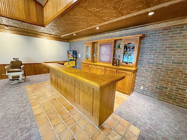 bar featuring brick wall, crown molding, light tile patterned floors, and wood walls