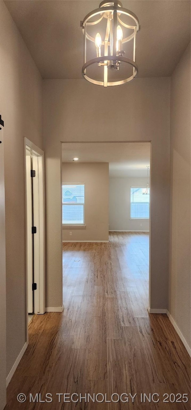 hall with wood-type flooring and an inviting chandelier