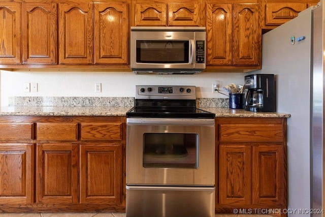 kitchen featuring appliances with stainless steel finishes, light stone counters, and light tile patterned flooring