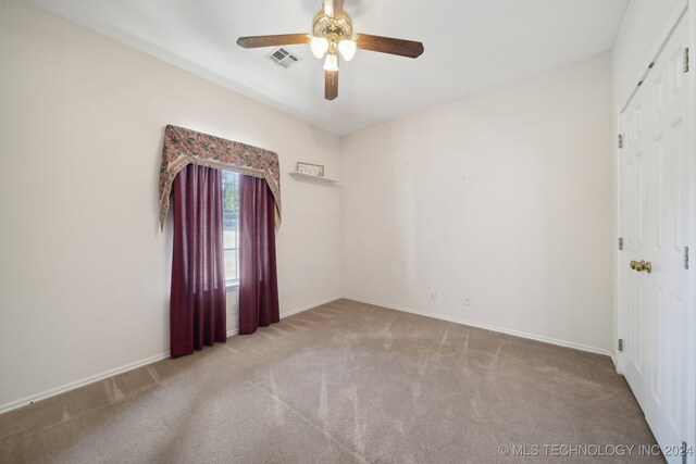 carpeted spare room featuring ceiling fan