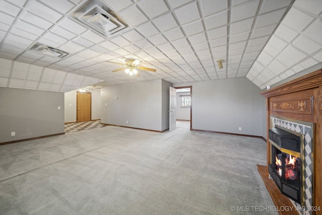 unfurnished living room featuring ceiling fan, carpet floors, and a tile fireplace