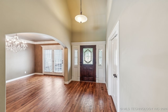 entrance foyer with ornamental molding, a high ceiling, a notable chandelier, and dark hardwood / wood-style flooring